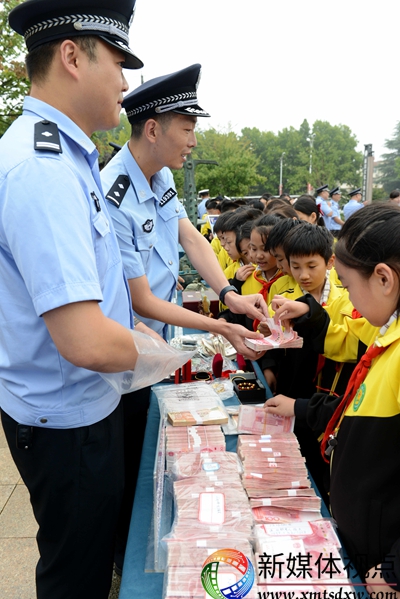 9月30日，枣庄市公安局山亭分局民警在夏季治安打击整治成果展现场，向学生展示破案追缴的现金。.jpg